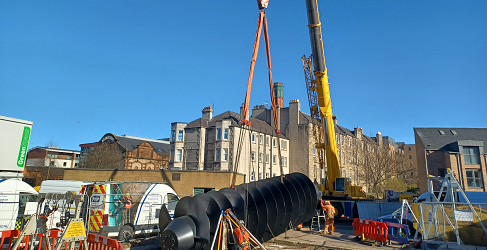 The screw pump is shown being lowered into place by a crane during the major operation