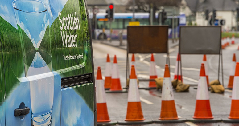 Back of a Scottish Water van next to road traffic cones and signage